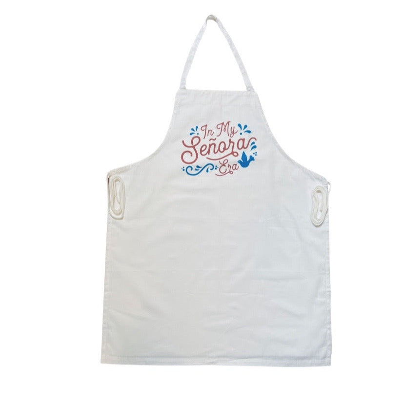 white apron with the phrase In My señora era in brown lettering and features a blue bird and filagree