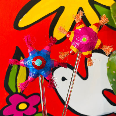Brightly colorful star piñata glass stir sticks (style 1). Tassels at the end of each point of the star piñata. Glass stir sticks pictured in front of Artelexia Frida mural.