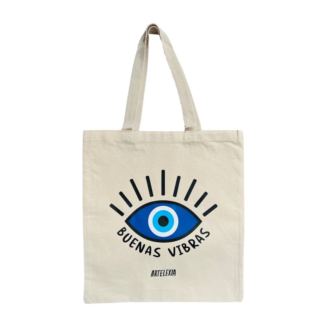 Natural canvas tote bag that features an evil eye image with the phrase Buenas Vibras in black lettering.