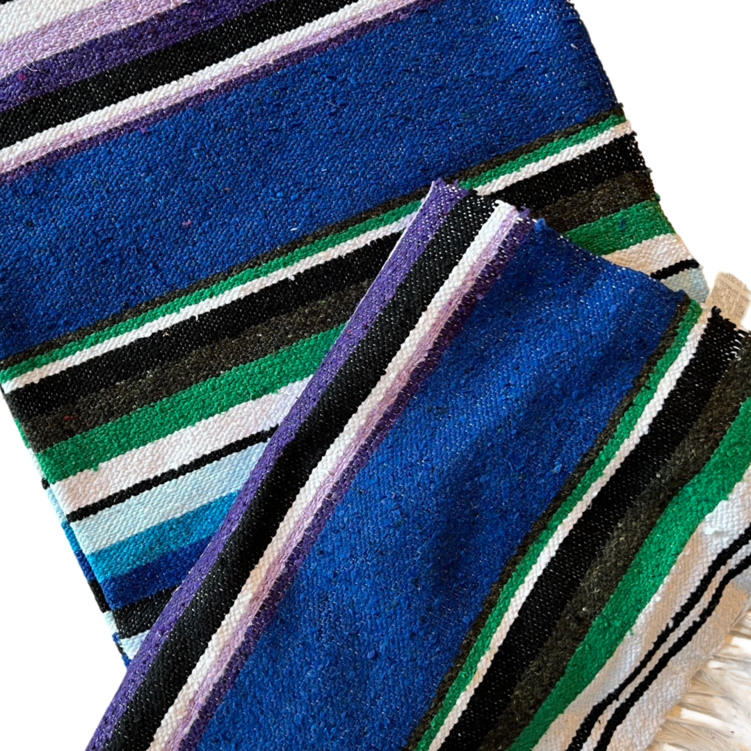closeup view of a royal blue serape striped blanket folded in half.