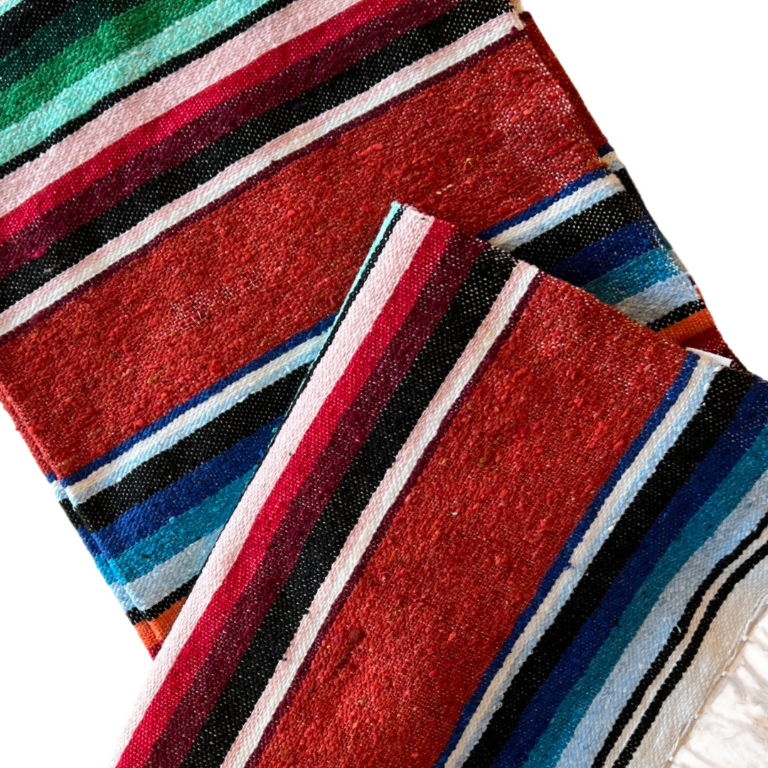 close up of rust colored serape striped blanket folded in half.
