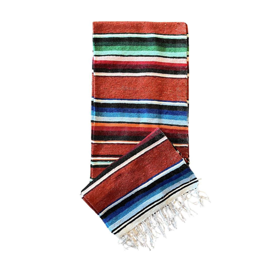 rust colored serape striped blanket folded in half.