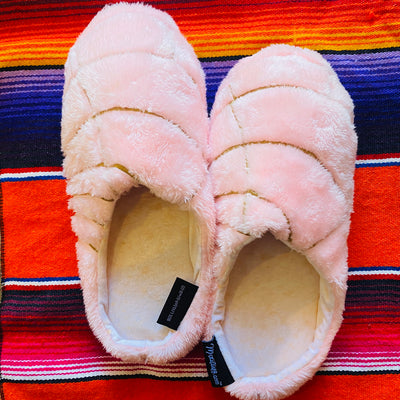 Top view of light pink concha pantuflas (slippers). Slippers pictured with red serape blanket.