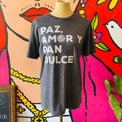 Dark gray unisex, "Paz, Amor Y Pan Dulce" phrase t-shirt with white detail pictured on mannequin.