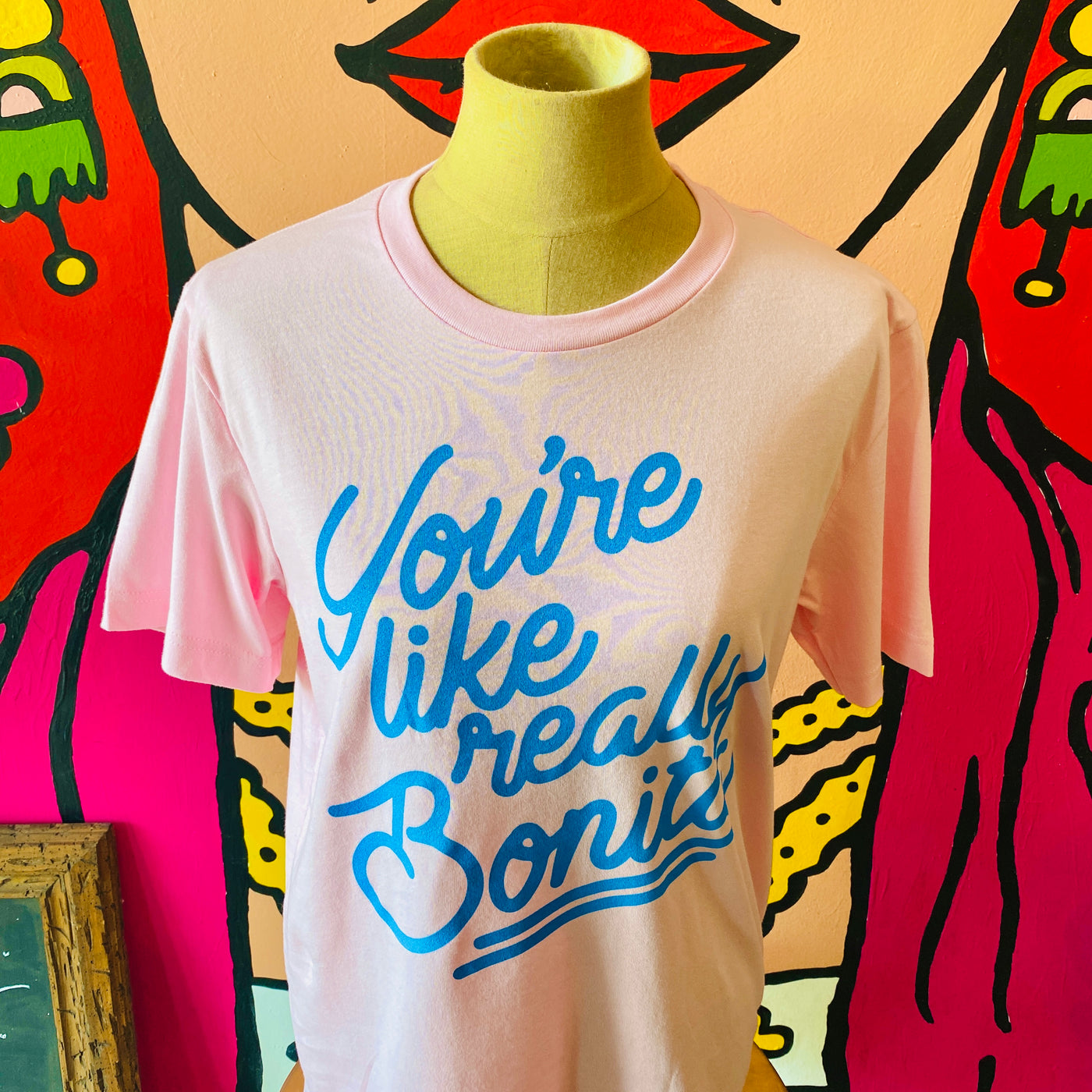 Close up of pink, "You're Like Really Bonita" phrase t-shirt with light blue detail.