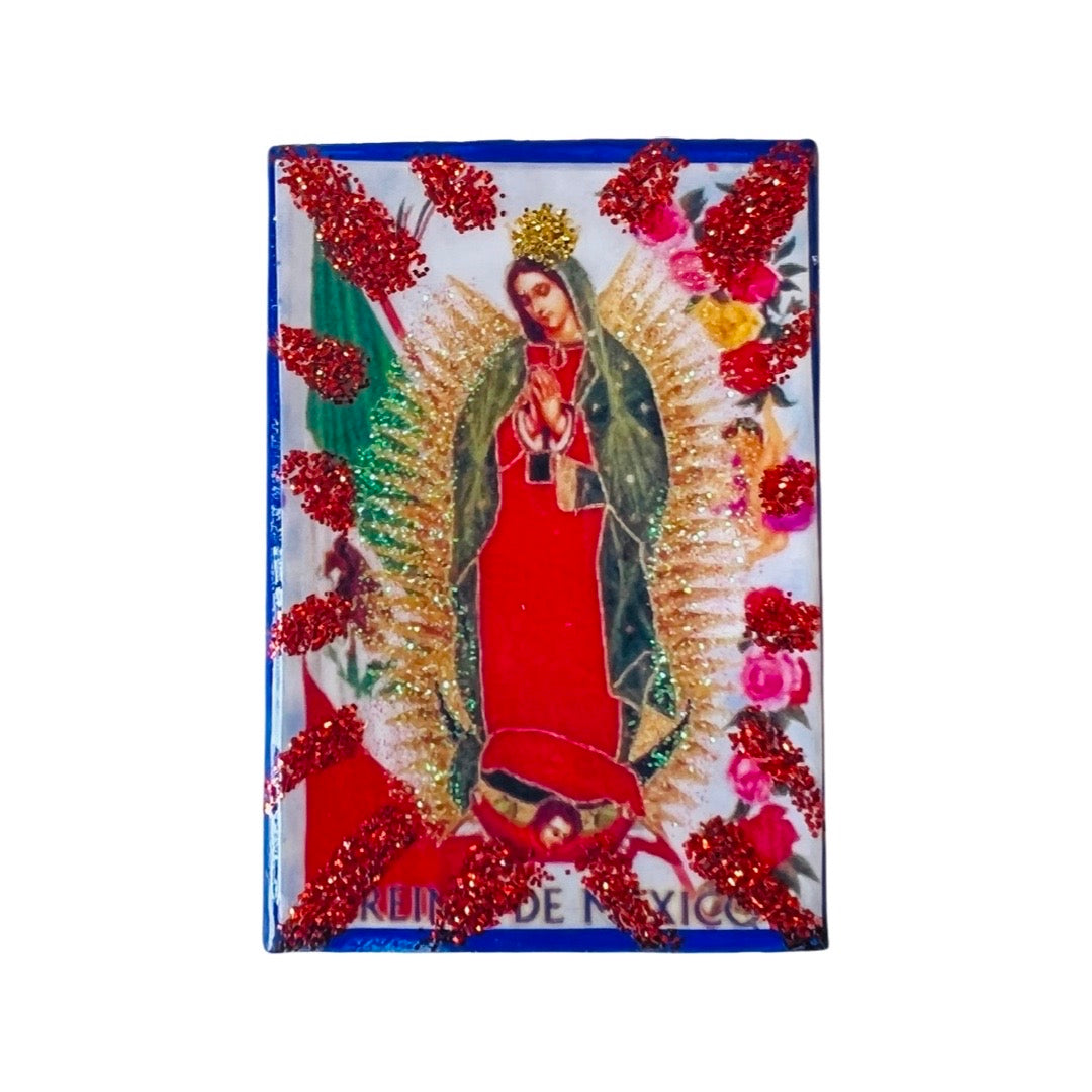 Matchbox with the Virgen de Guadalupe in front with gold and red glitter on the sides.