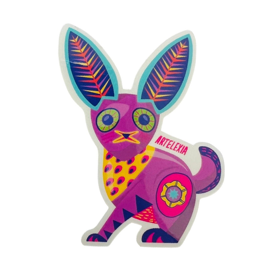 Purple bunny in the style of an alebrije featuring yellow, pink, green, blue and teal colors. 
