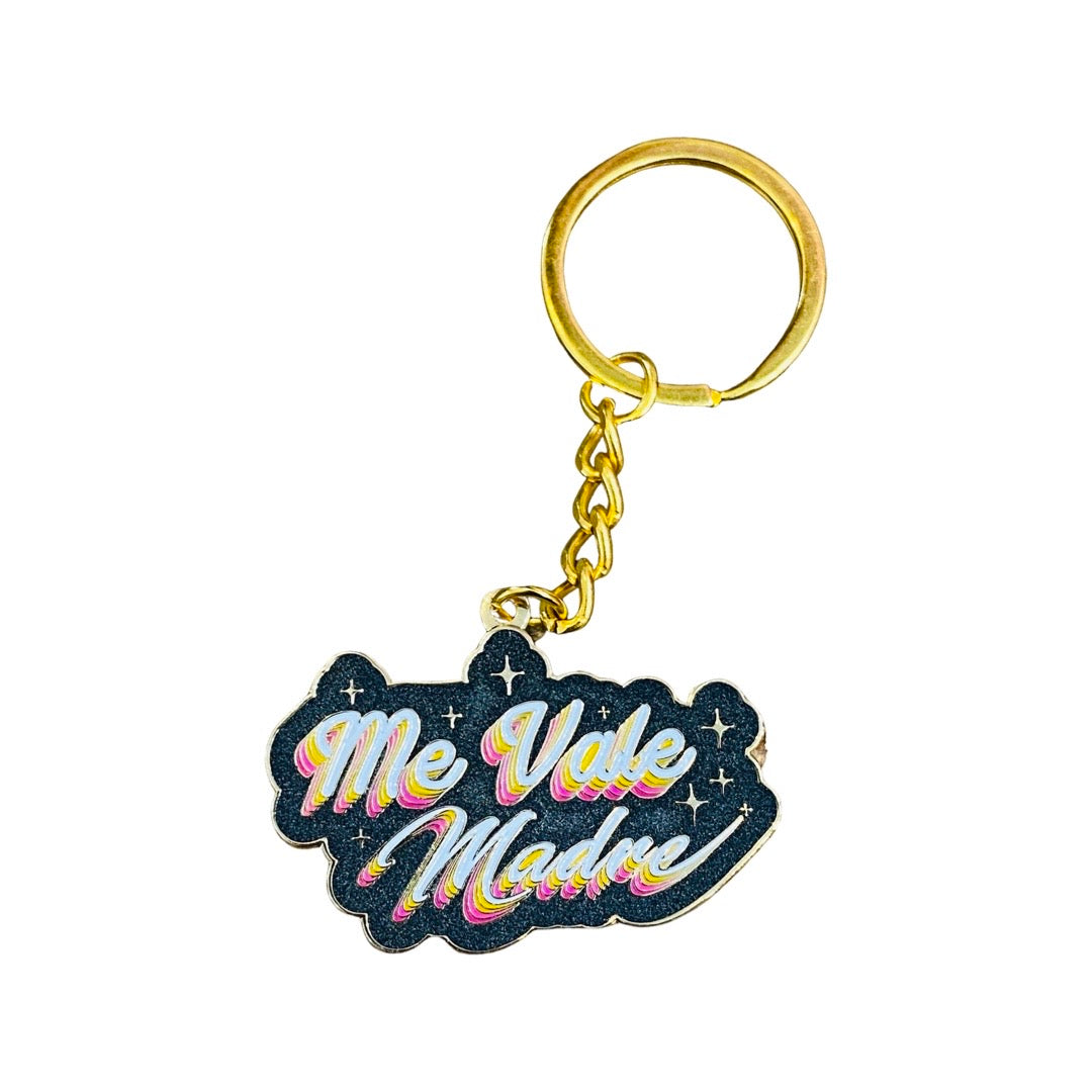 Me Vale Madre (I don't care) phrase enamel keychain with gold hardware. Multicolored cursive lettering with black background with stars. 