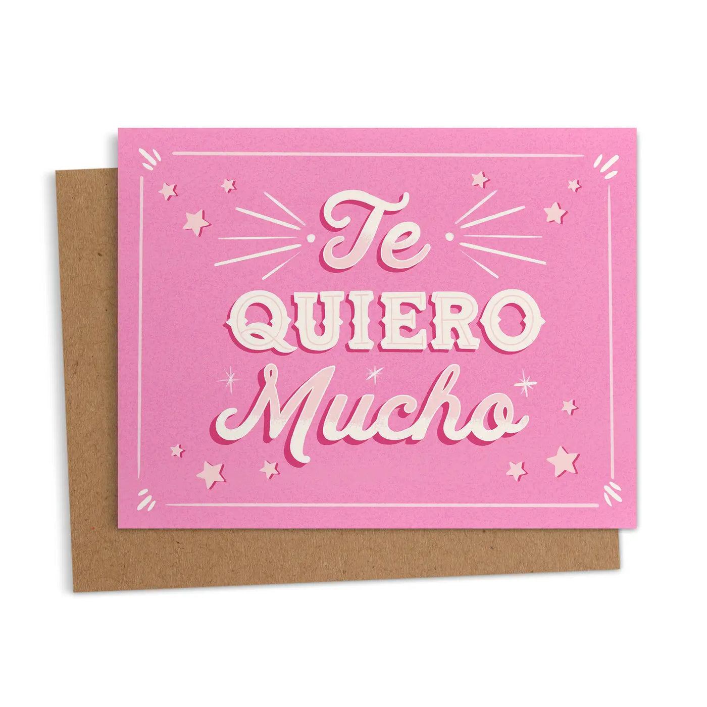 A pink greeting card with white text reading "Te Quiero Mucho," surrounded by star and sparkle accents, accompanied by a kraft envelope.