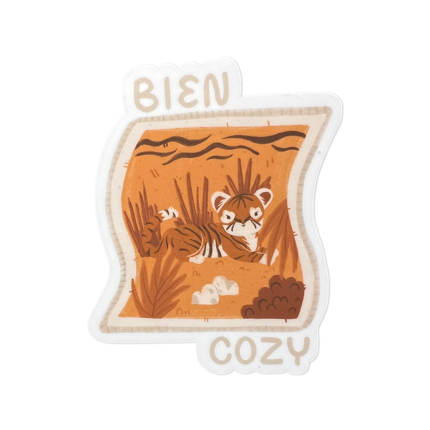 A tan and light orange image of a blanket with a tiger on it and the phrase Bien Cozy in tan lettering.