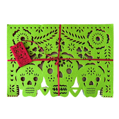 green felt papel picado inspired placemat that features a trio of skulls design with flowers and bone crosses.