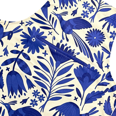 Close up view of apron featuring a blue Mexican otomi design with front pocket, blue neck and waist ties.