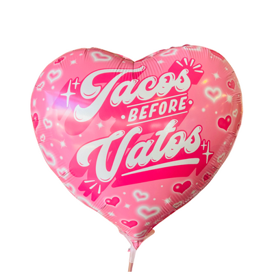Pink heart shaoed balloon with the phrase Tacos Before Vatos in white lettering.