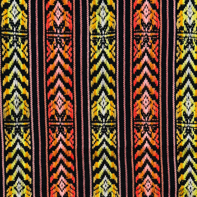 close up view of a Colorful woven Cambaya table runner from Mexico, featuring intricate geometric patterns in yellow, orange, and black with multicolored fringed ends.