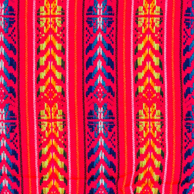 a close up view of a Colorful woven Cambaya table runner from Mexico, featuring intricate geometric patterns in blue, yellow, and pink with multicolored fringed ends.