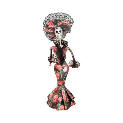 Día de Muertos Catrina figurine in a black gown with pink floral patterns, paired with black lace accents and a wide-brimmed lace hat, handcrafted from papier-mâché.