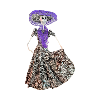 Hand-painted Día de Muertos dancing skeleton figurine made of paper mache, wearing a black and white dress with purple lace-trimmed hat and posed in a dancing stance.