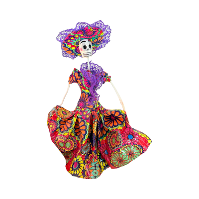 Hand-painted Día de Muertos dancing skeleton figurine made of paper mache, wearing a colorful dress with lace-trimmed sombrero and posed in a dancing stance.