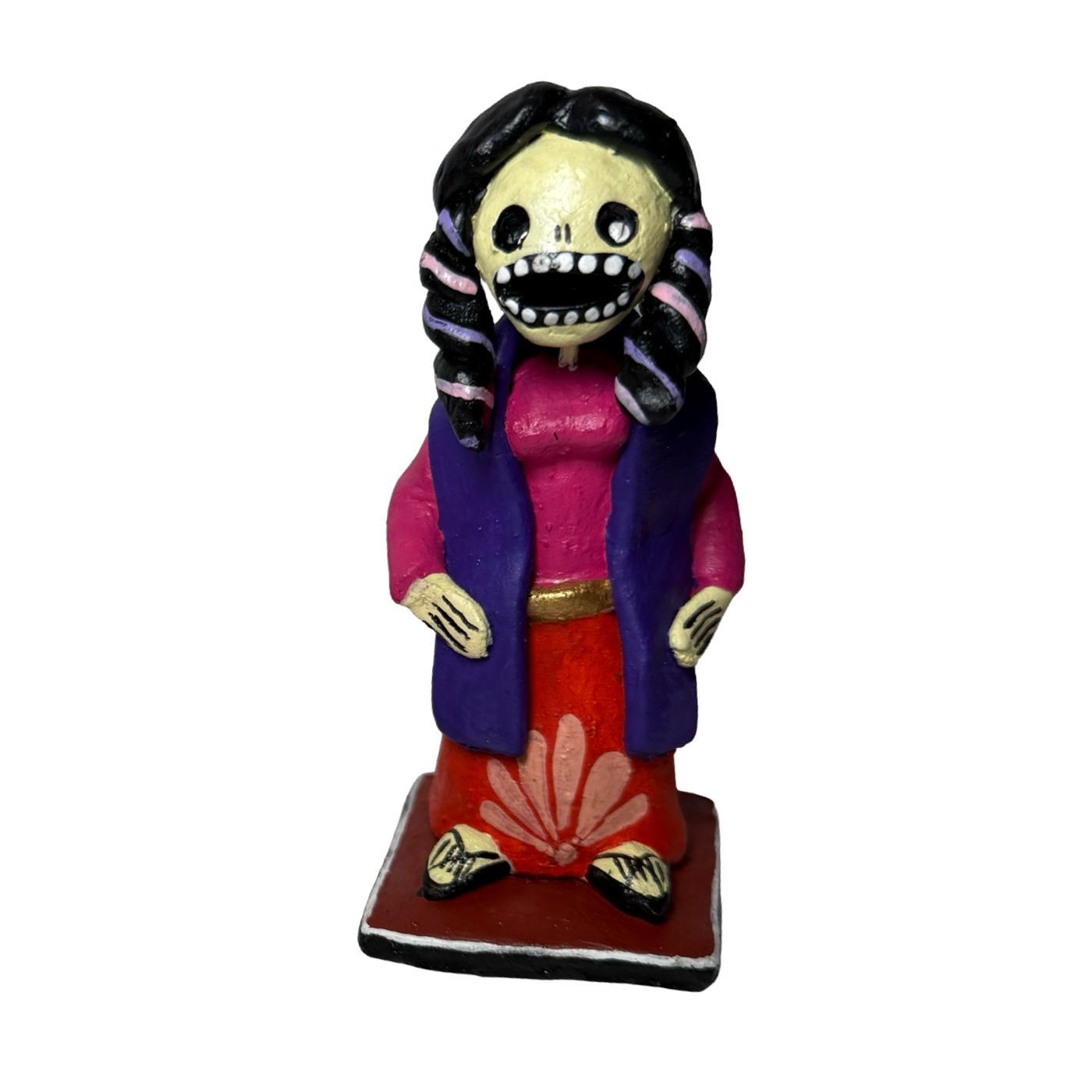 Colorful hand-painted Día de Muertos skeleton figurine in traditional clothing with braids standing on square base.