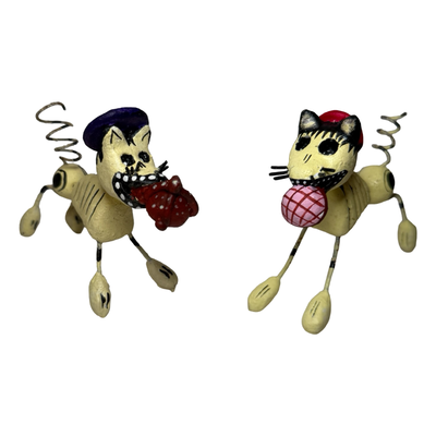 Two handcrafted Día de Muertos skeleton cat figurines with spring tails and painted sombreros. One cat holds a concha bread in its mouth, while the other carries a pan dulce roll, both decorated in festive detail.