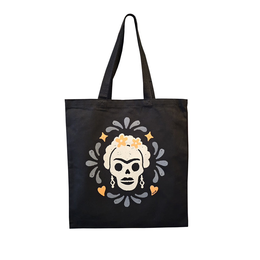 Black canvas tote bag featuring a cream colored Calavera resembling Frida Kahlo, surrounded by orange & grey accents