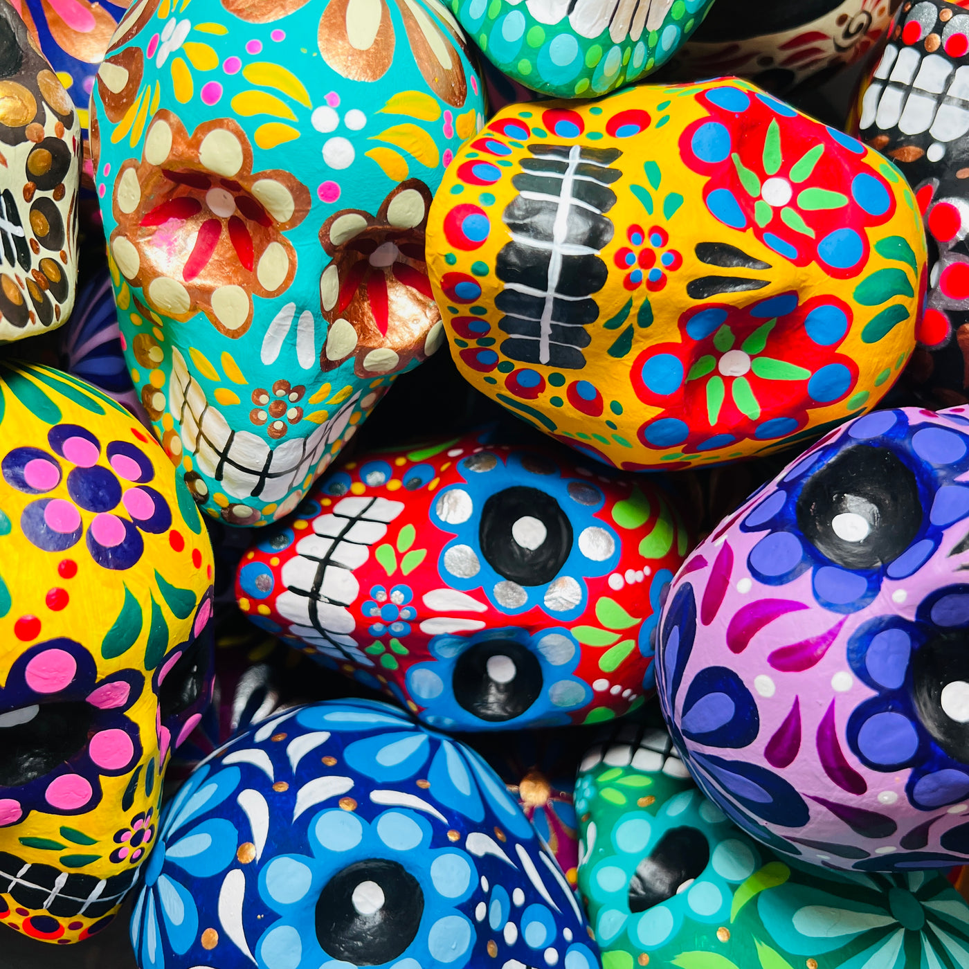 close up view of a pile of view of multi-colored paper mache sugar skulls