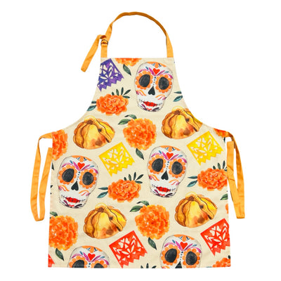 beige apron with images of sugar skulls, pan de muerto, marigolds and papel picado banner featuring orange waist and neck ties.