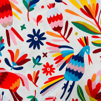 close up view of a cream kitchen towel with a mutli-colored otomi design