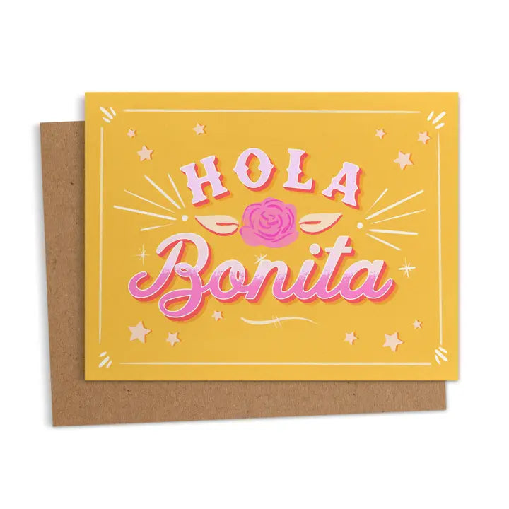 Greeting card with the words “Hola Bonita” in bold pink letters with a rose and star accents on a yellow background.