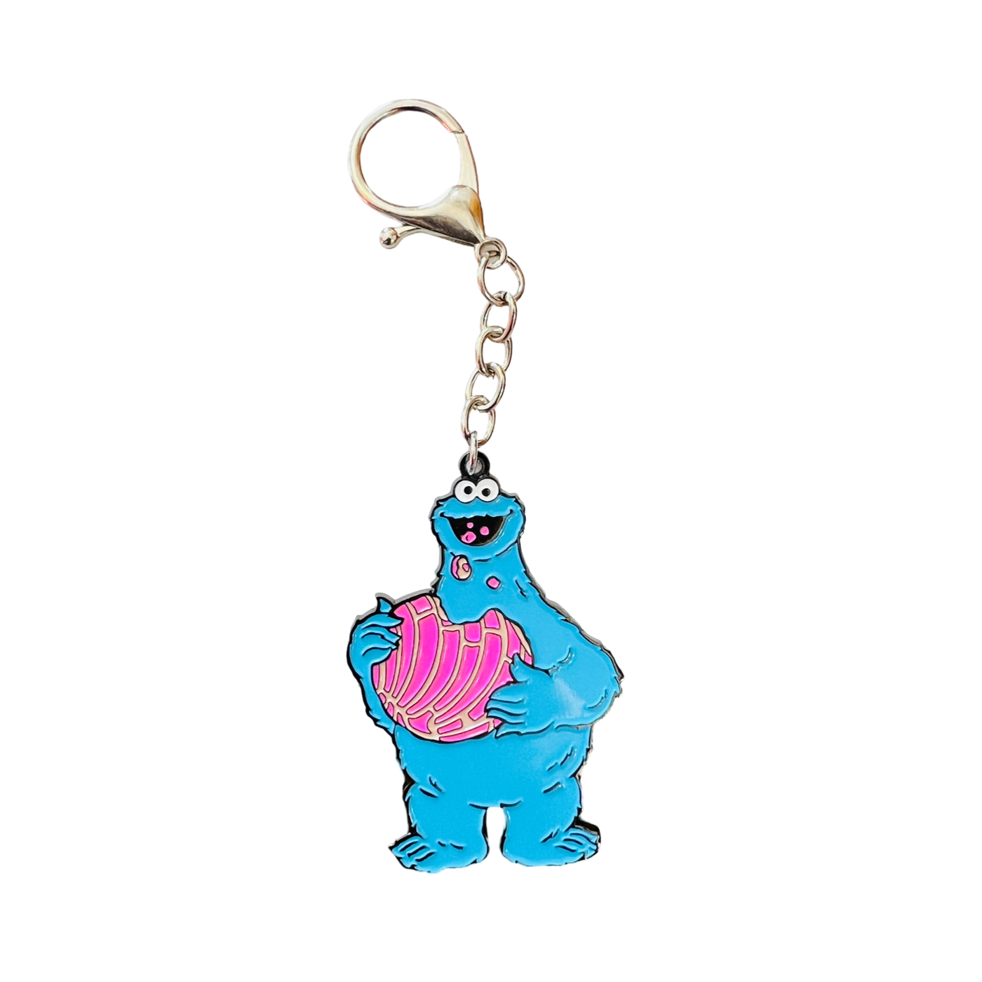 enamel keychain of a blue furry monster eating a pink concha featuring a silver chain and clip.