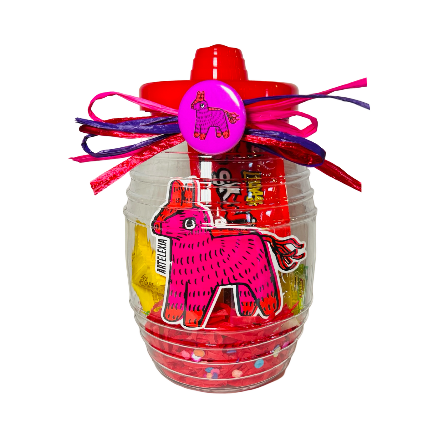 A clear candy jar decorated with vibrant ribbons and filled with colorful confetti, assorted Mexican candies, and a pink pin-back button featuring a piñata design. The jar also includes a matching pink sticker with a playful piñata illustration.