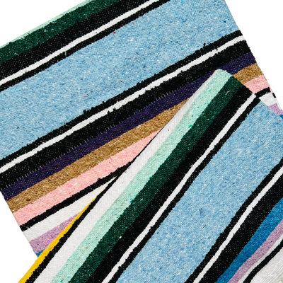 close up of light blue serape striped blanket folded in half.