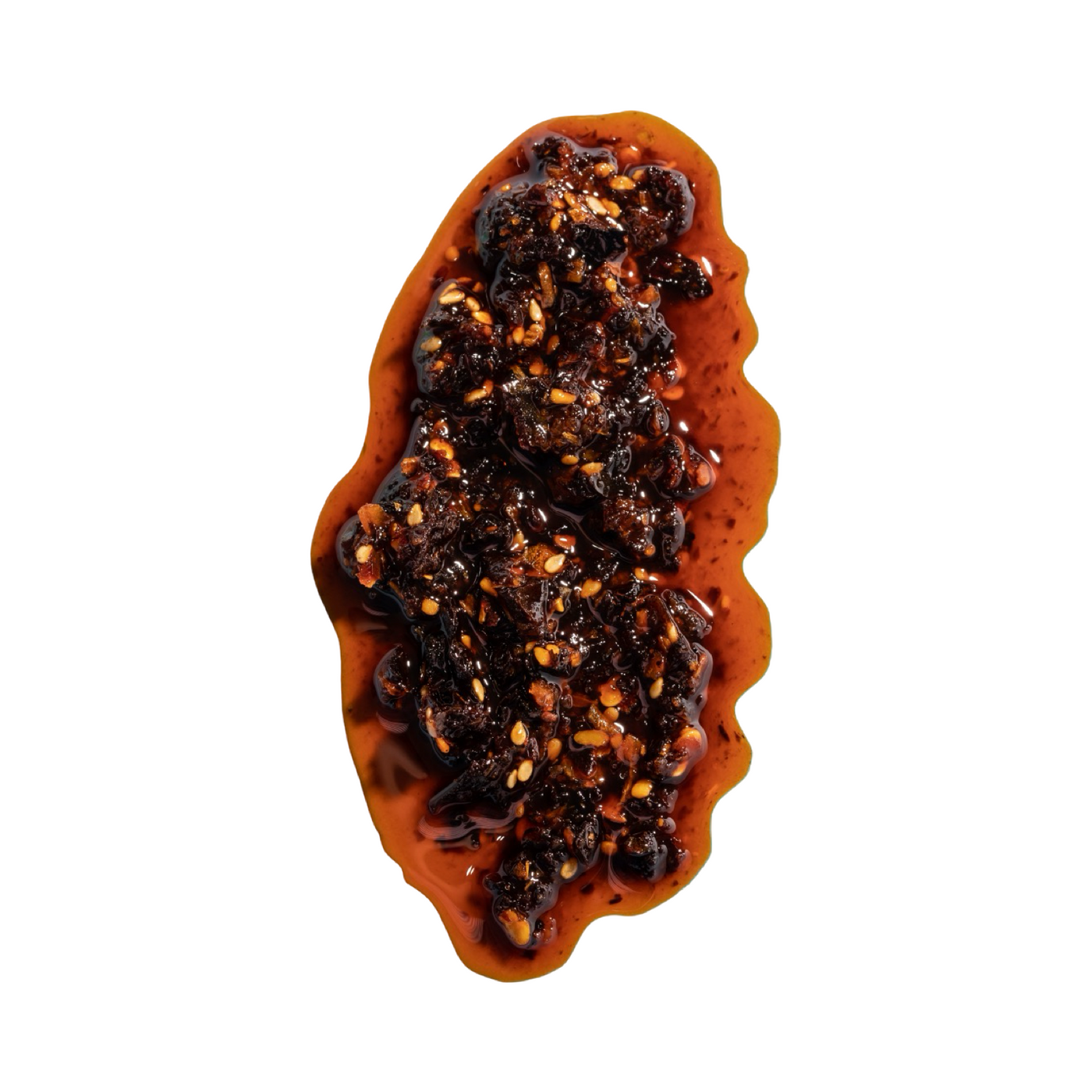 Close-up of a spoonful of chili crisp, featuring crunchy dried chili flakes, seeds, and bits of pepper suspended in rich, red chili oil, against a white background.