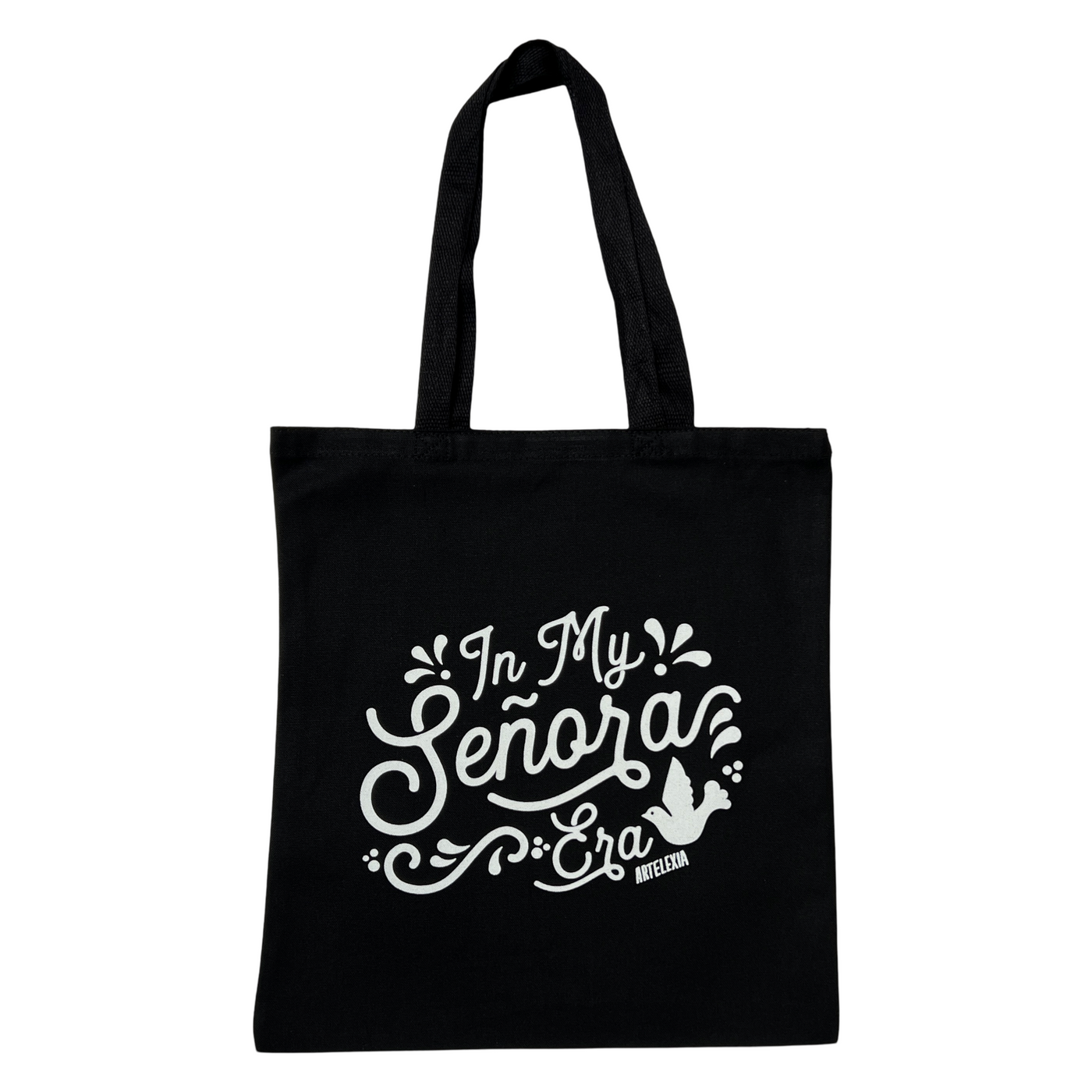 black canvas tote bag with the phrase In My Senora Era in white lettering and featuring an image of a white bird with some filagree