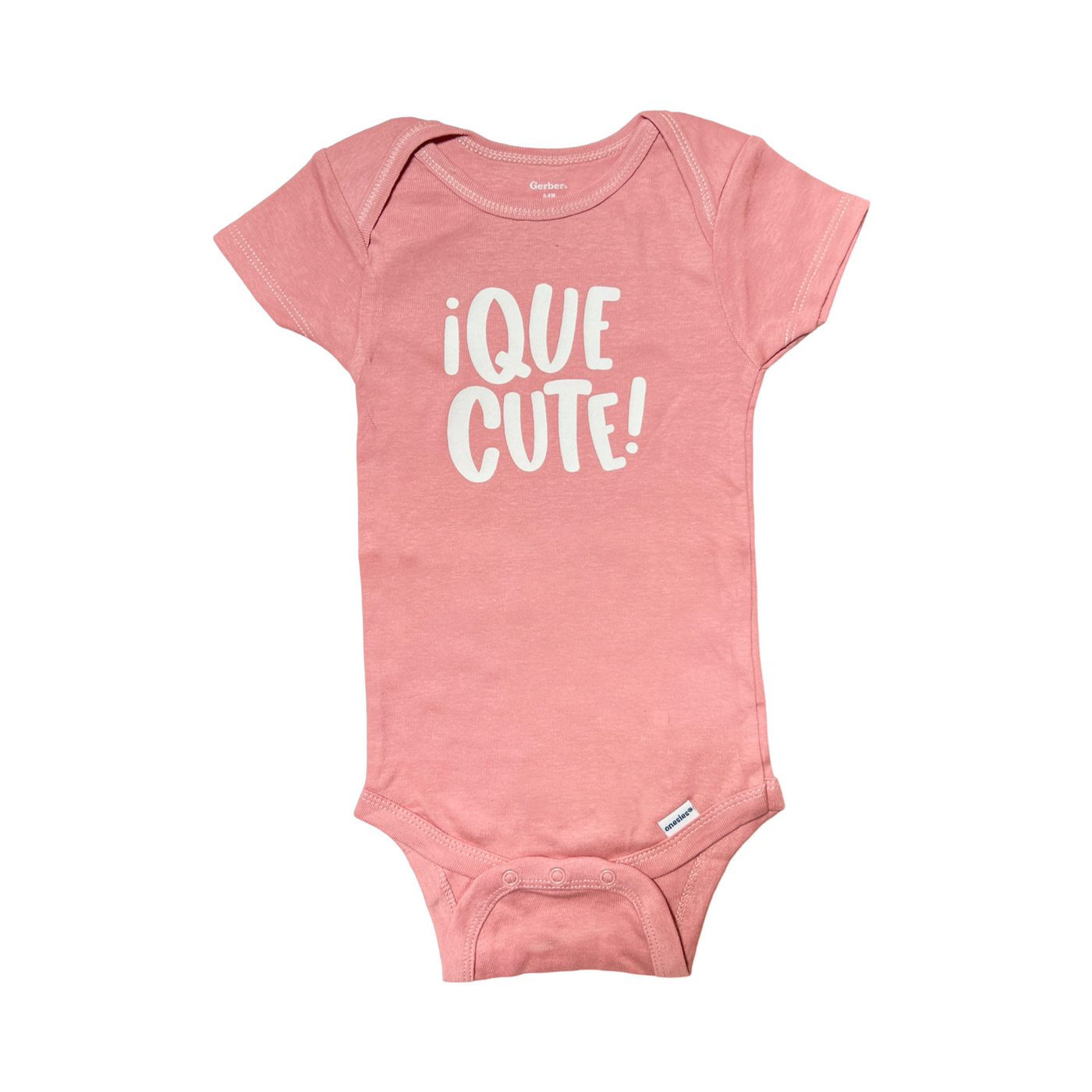 Pink colored onesie with the phrase Que Cute in white lettering