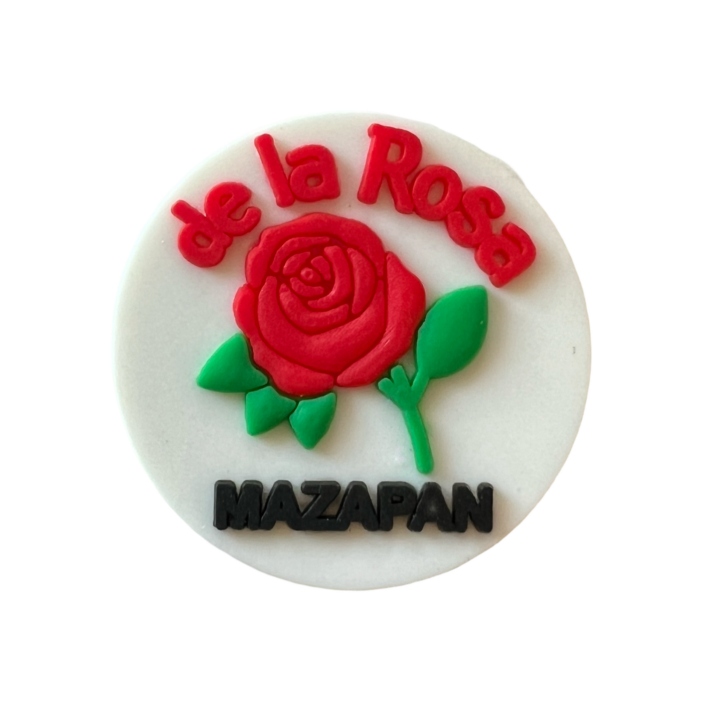 white round croc charm with a red rose in the center and the phrase De La rosa Mazapan in red and black lettering, respectively.