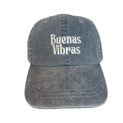 front view of a heathered blue hat with the phrase Buenas Vibras in white lettering