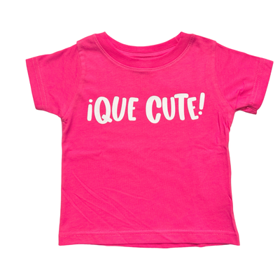 pink shirt with the phrase Que Cute in white lettering