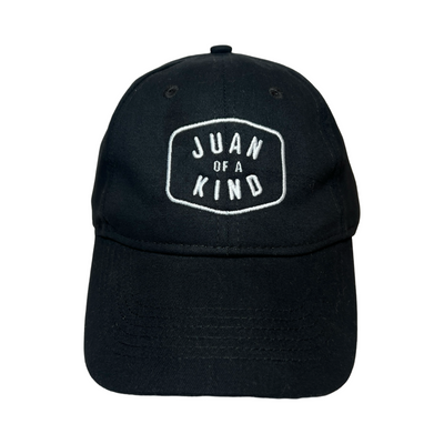 Front View of a black hat with the Phrase Juan of a Kind in white letteing