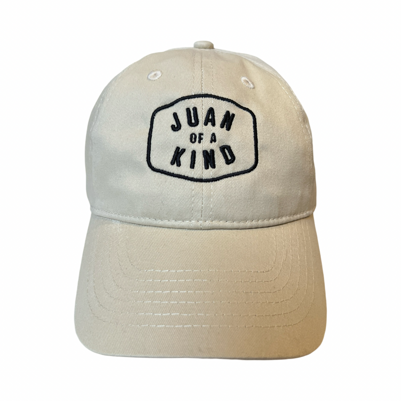 front view of a cream hat with the phrase Juan of a Kind in black lettering