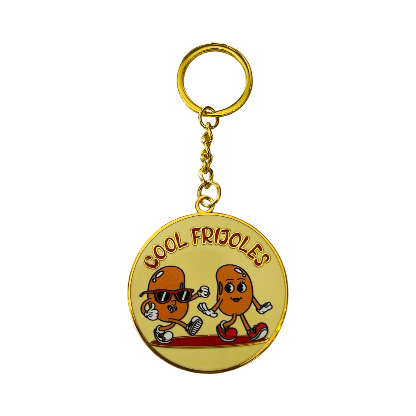 Round gold enamel that features an image of two animated beans and the phrase Cool Frijoles in red lettering.