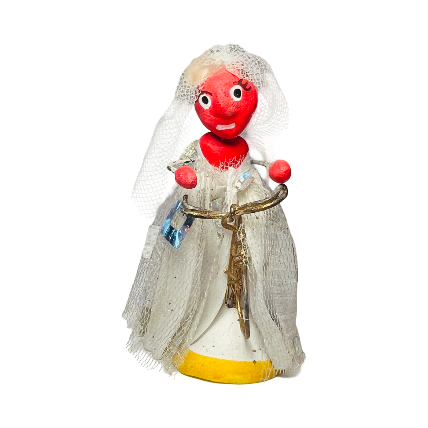 red diablita figurine in a wedding dress riding a bike