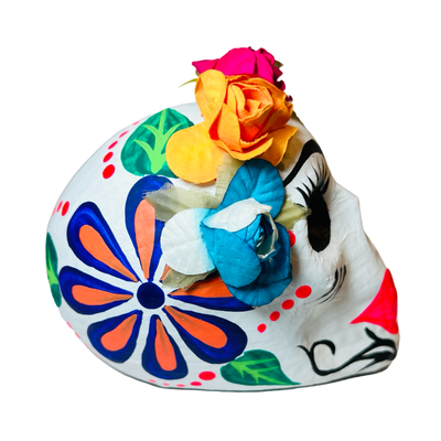 side view of a colorful paper mache frida sugar skull in multiple colors featuring a flower crown.