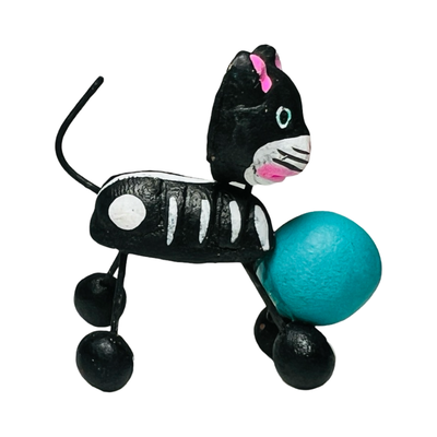 black cat calavera figurine playing with a teal ball