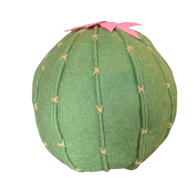 side view of a felt light green cactus  shaped pillow with a pink flower on top.