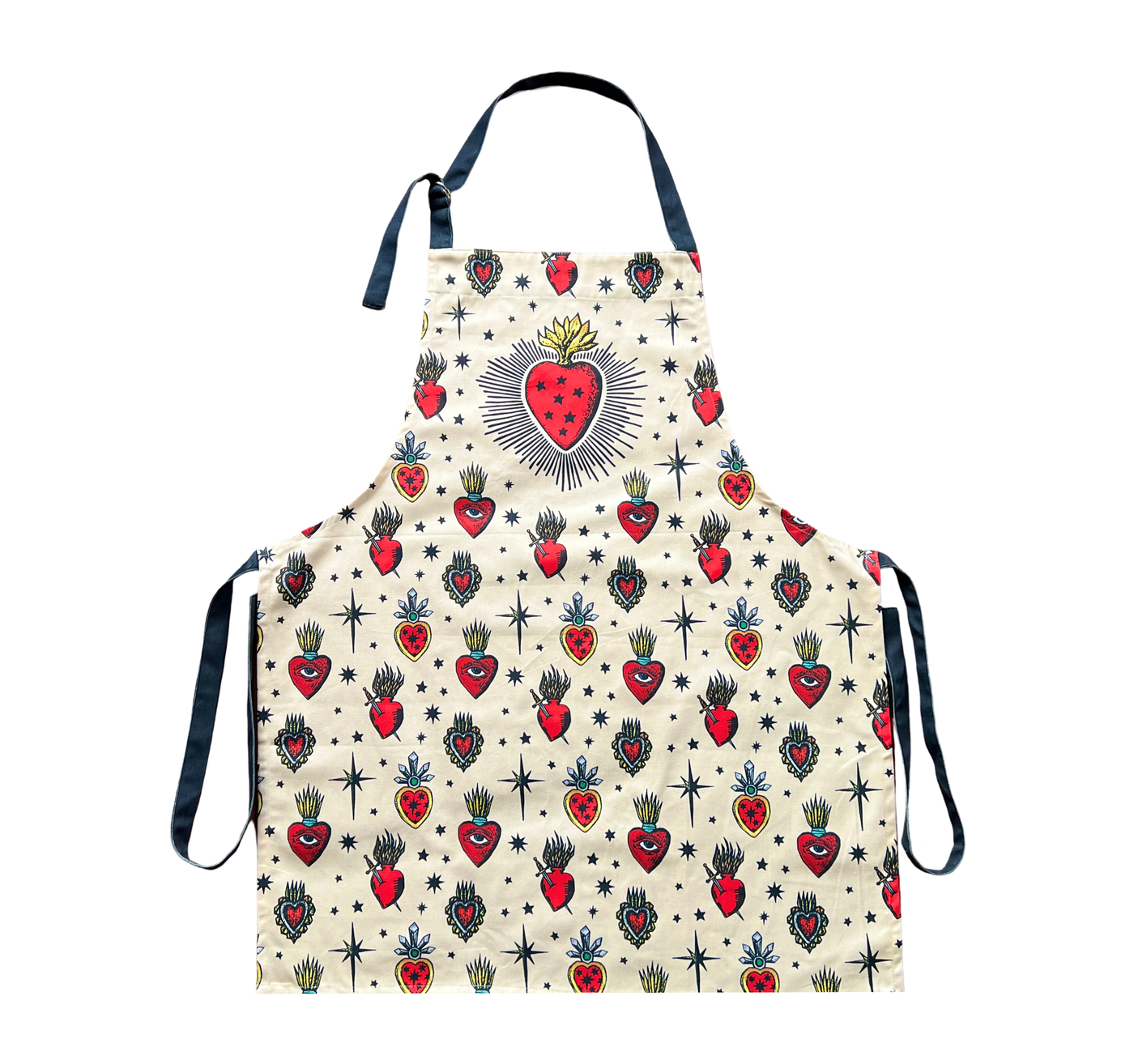 cream apron with various images of sacred hearts with eyes, stars and daggers in the center of them. Features dark gray neck and waist ties.