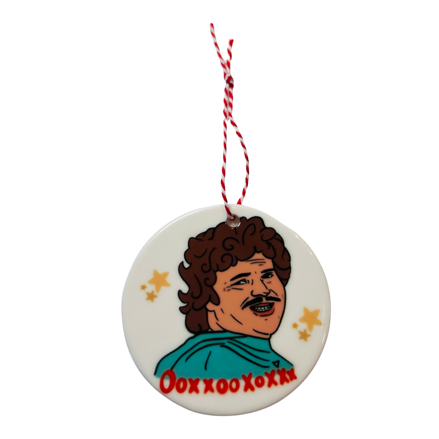 Round ceramic ornament featuring a stylized image of Nacho Libre with curly hair, a teal cape, and the phrase "OooxxooXoXxx" in red text, surrounded by golden stars.