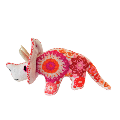 side view of a white felt triceratops with a floral embroidered design
