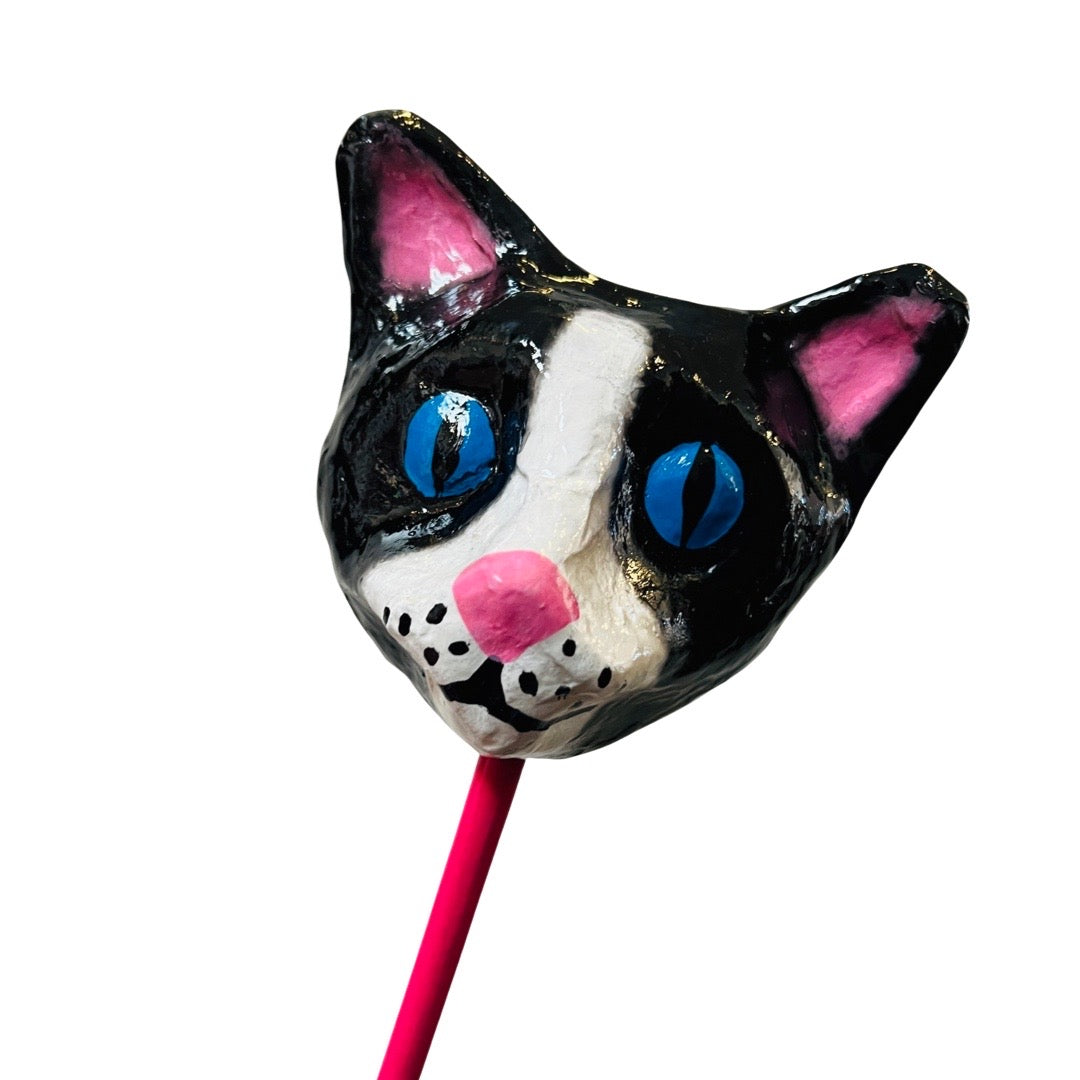 black and white paper mache cat shaker with a pink handle