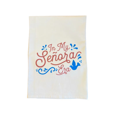 Natural towel with the phrase In My Senora era in brown lettering featuring a blue bird and filagree. towel folded in quarter